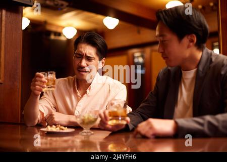 Japanese friends having a drink at a bar counter Stock Photo