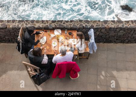 La Palma Island Spain - March 05, 2022: Top view family having lunch outside on a terrace besides the sea Stock Photo