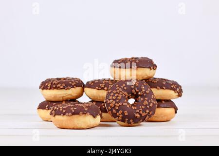 Donuts glazed with chocolate and with sprinkles on white wooden background with copy space Stock Photo