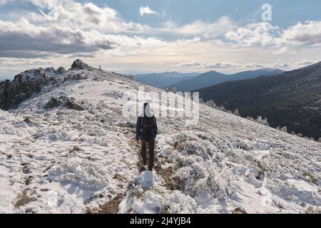 Unrecognizable traveler walking on snowy mountain Stock Photo