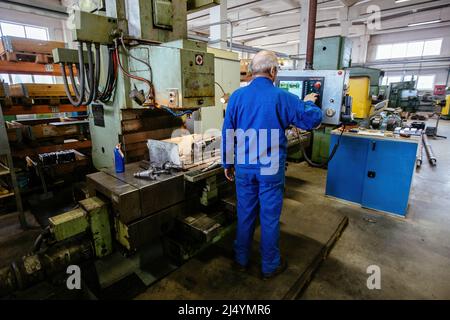 Factory engineer adjusting operation parameters of CNC lathe machine. Stock Photo
