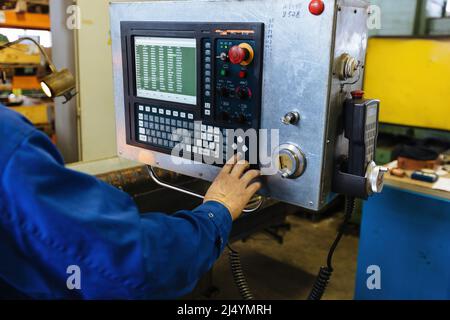 Factory engineer adjusting operation parameters of CNC lathe machine. Stock Photo