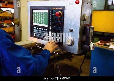 Factory engineer adjusting operation parameters of CNC lathe machine. Stock Photo