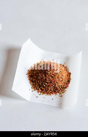 Chilli flakes and herbs on paper Stock Photo