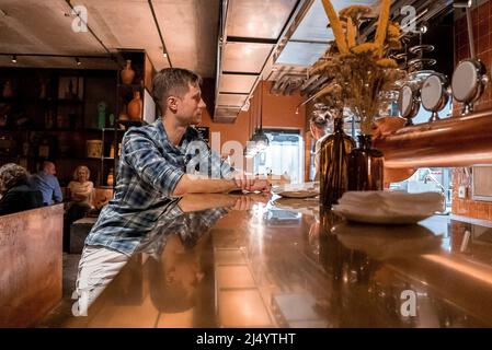 Young tourist sitting at bar counter in restaurant at luxurious ski resort Stock Photo