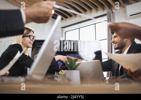 Shaking hands, business concept. Side view of pretty young smiling caucasian businesslady, shaking her hand of male indian colleague in black suit, during meeting in modern office. Stock Photo