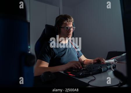 young blond man playing video games, playing on his laptop computer at night Stock Photo