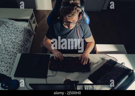 young blond man amateur video game player, playing online on laptop at night. Stock Photo