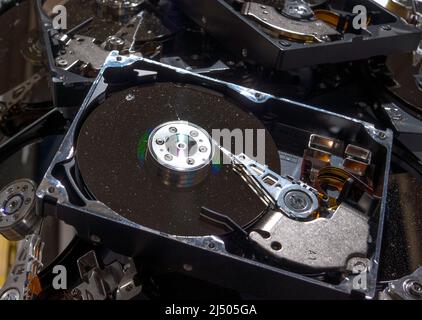 Computer hard drives being recycled. The drives have the tops removed, and are dirty and dusty. The view is from the upper side. Stock Photo