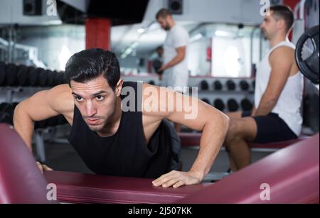 Man doing incline push-ups in gym Stock Photo