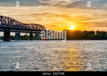 The sun sets over the Arkansas shore by the Harahan Bridge on the Mississippi River by Memphis, Tennessee. Stock Photo