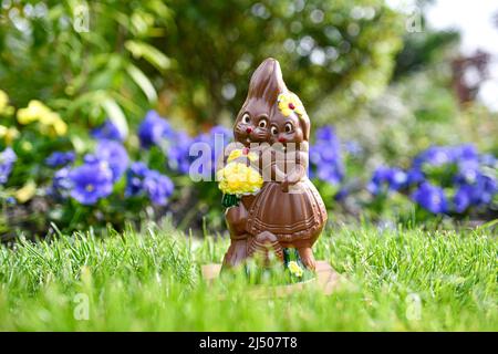 Illustration picture shows a milk chocolate Easter egg, a pair (couple) of bunnies lies in a garden among spring flowers during an Easter eggs hunt in Paris, France. Stock Photo