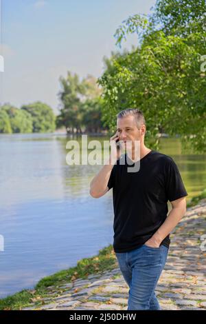 Mature businessman talking on cell phone at a lake Stock Photo