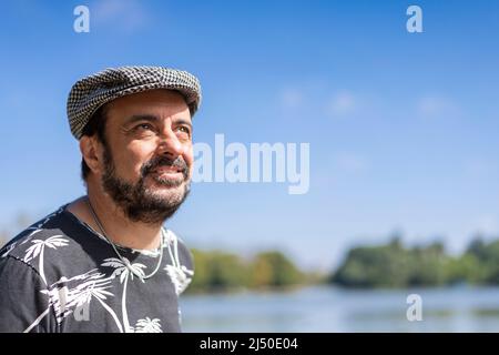 Bearded mature man wearing a beret at a lake. Copy space Stock Photo