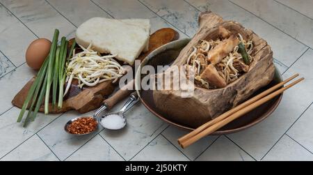 Stir fried soft turnip cake or Fried radish cake (chai tow kway) with bean sprout and chives in ceramic plate served with suger, ground dried chili. T Stock Photo