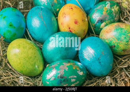 Metallic shimmering buten Easter eggs in blue green colors on straw, close-up Stock Photo