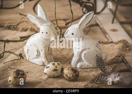 Wooden decoration Easter bunnies with small quail eggs and natural decoration on rustic wooden background Stock Photo