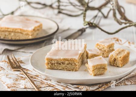 Pieces of covered apple pie with sugar icing on a white wooden background. Harmonious color concept in beige tones. Stock Photo
