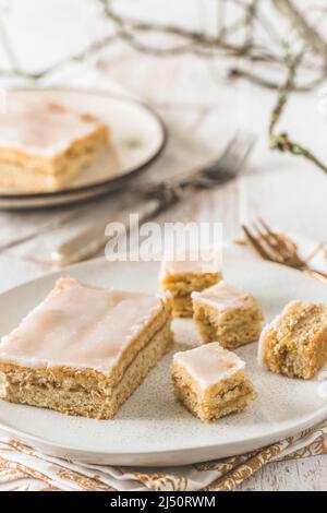 Pieces of covered apple pie with sugar icing on a white wooden background. Harmonious color concept in beige tones. Vertical. Stock Photo