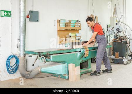 Carpenter working at woodworking planer in workshop Stock Photo
