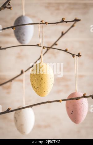 Colorful decorative easter eggs in pastel colors on autumn branches, vertical Stock Photo