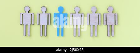 Figures of beige wooden little men in middle one blu Stock Photo