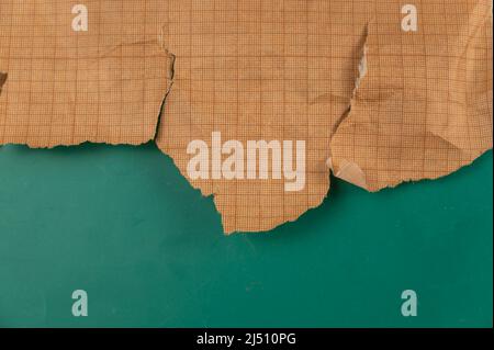 Ripped crumpled sheet of millimeter graph paper against a green background. Brown paper for drafting, design, engineering, and more. Abstract multitas Stock Photo