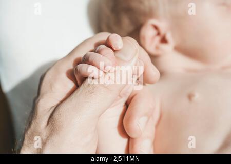 Baby's hand. The father holds with tenderness and love the small hand of the newborn. New life, parental protection, care, love, child and baby health. High quality photo Stock Photo