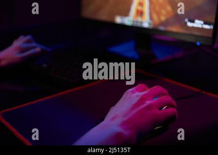 Professional gamer play computer video game in dark room, use neon colored rgb mechanical keyboard, place for cybersport gaming Stock Photo