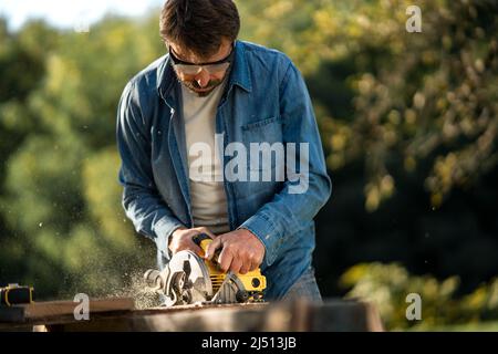 Craftsman working with circular saw at construction site Stock Photo