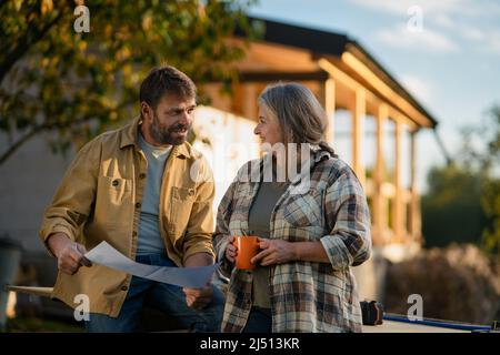 Mature couple having coffee break when working together on construction site of their new house. Stock Photo
