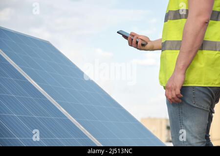 Unrecognizable person using phone for controlling photovoltaic solar station. Stock Photo