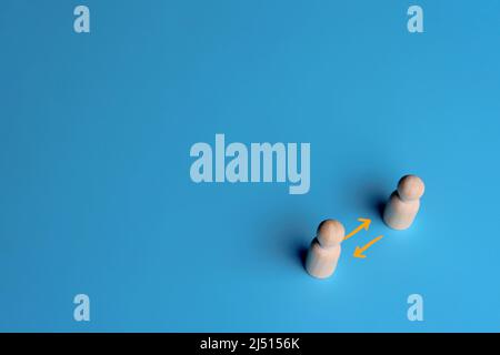 Wooden dolls and exchange arrow on blue background. Copy space. Share, network, peer to peer concept Stock Photo