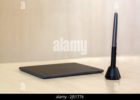 Graphics tablet and pen stand on table with selective focus on stylus. Horizontal photo. Stock Photo