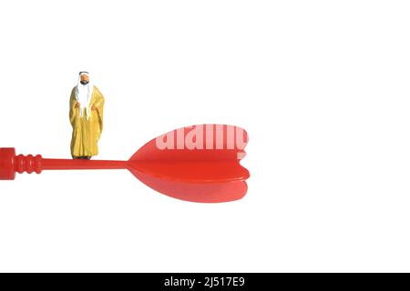 Miniature people toy figure photography. A Sultan wearing yellow bihst (king cloak) standing above flying red arrow. Isolated on white background. Ima Stock Photo