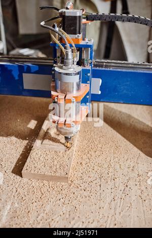 High angle medium close-up no people shot of CNC milling machine drilling hole in wooden plank Stock Photo