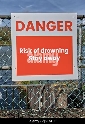 Danger risk of drowning signs alongside open deep water for safety ...