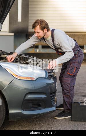 Car mechanic in uniform checking engine. Auto repair service. Engine specialist fixing motor. Copy space. Stock Photo