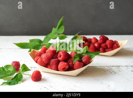 Fresh raspberries in the wooden bowls - boats with leaves Stock Photo