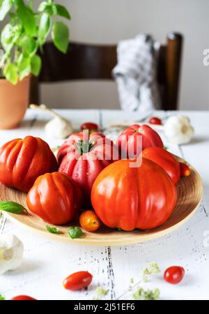 tomatoes on the plate and white wooden background with basil plant garlic and chair Stock Photo
