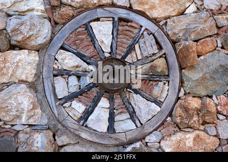 Old style wooden wheel in the stone wall Stock Photo