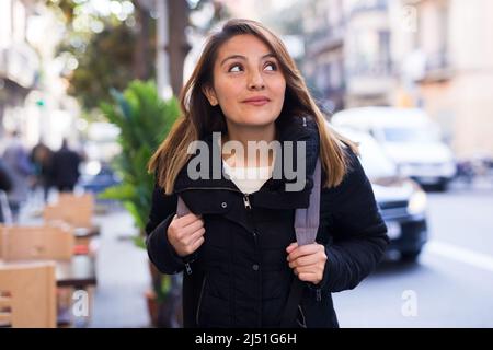 Positive latin american girl walking along city street Stock Photo