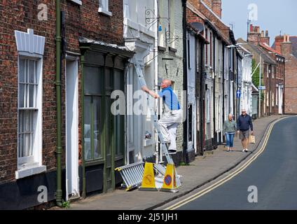 Man painting house on Soutter Gate in Hedon, East Yorkshire, England UK Stock Photo