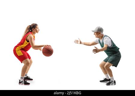 Full length profile shot of a female basketball player and an elderly man playing basketball isolated on white background Stock Photo