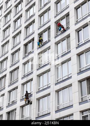 Industrial climbers wash windows on huge residential building. Working at height requires skills and abilities. Stock Photo