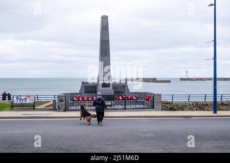 War Memorial at the seafront in the County Down coastal town of Donaghadee - with a view across the harbour to the Donaghadee lighthouse. Stock Photo