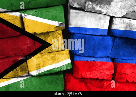 Concept of the relationship between Guyana and Russia with two painted flags on a damaged brick wall Stock Photo
