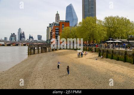 People on small sandy beach on the banks of The River Thames at low tide, South Bank, London, UK, April Stock Photo