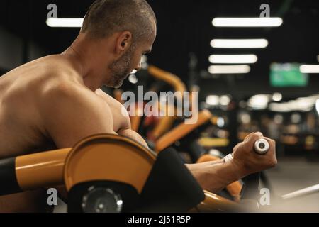 Muscular bodybuilder doing biceps curls during his workout in the gym Stock Photo