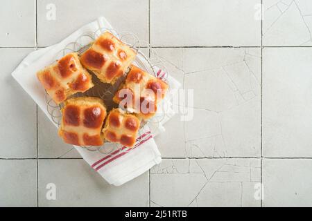 Easter hot cross buns with colored eggs Easter gingerbread rabbits and cookies over light grey old cracked tile table background. Spring holiday bakin Stock Photo